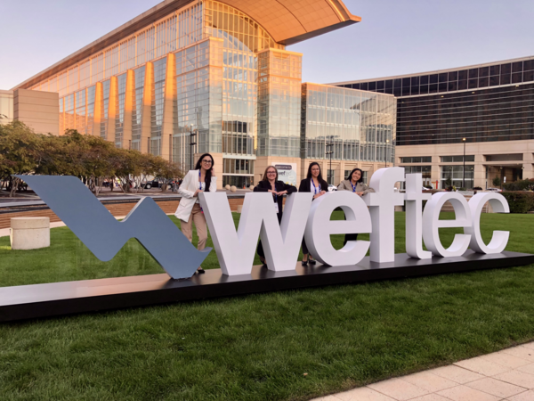 Senior Design Team at WEFTEC 2023 - standing by sign